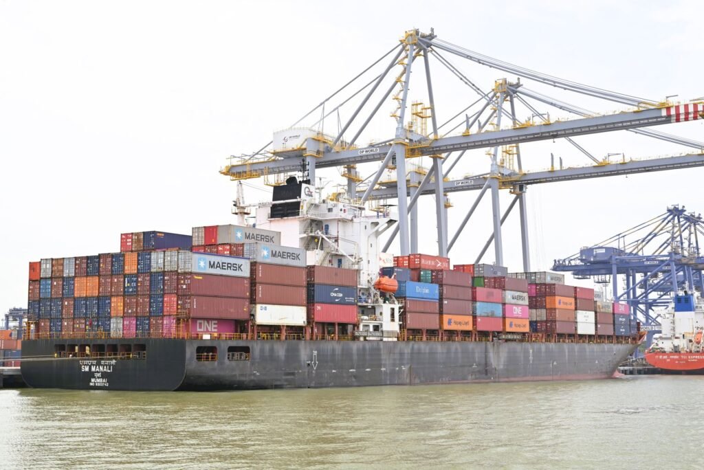 Cargo vessel moored at Kochi, Kerala, India, showcasing global container shipping with cranes in background.
