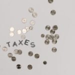A visually striking flatlay of coins with 'Taxes' text on a white surface, ideal for financial concepts.