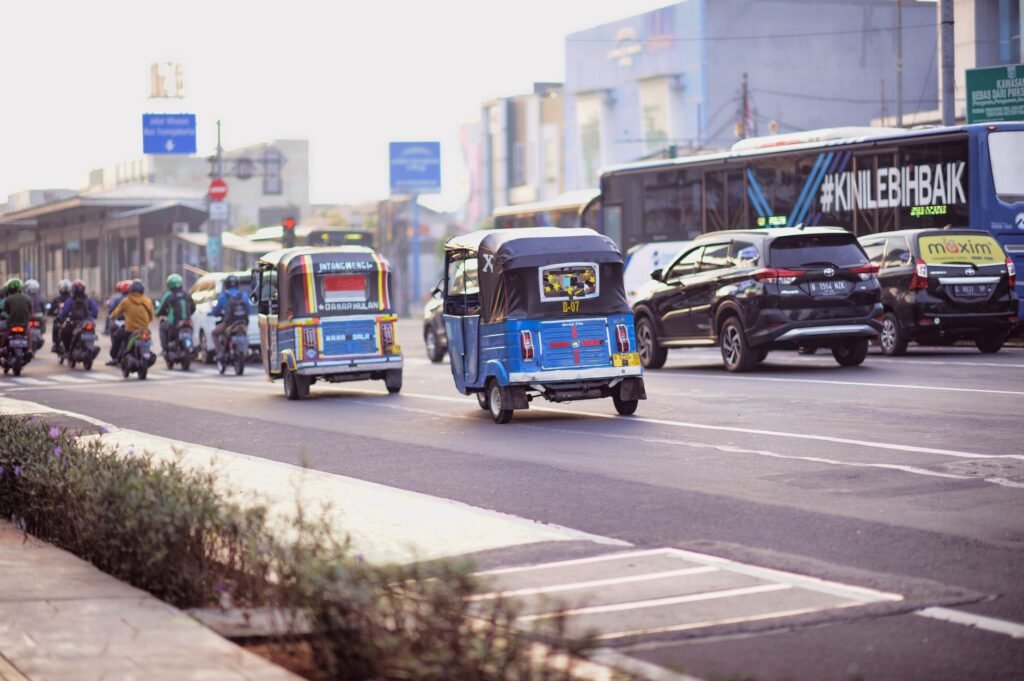 Morning traffic scene in Jakarta featuring diverse vehicles including bajajs and motorcycles.