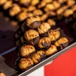 Close-up of roasted chestnuts on a metal tray, highlighting texture and color.
