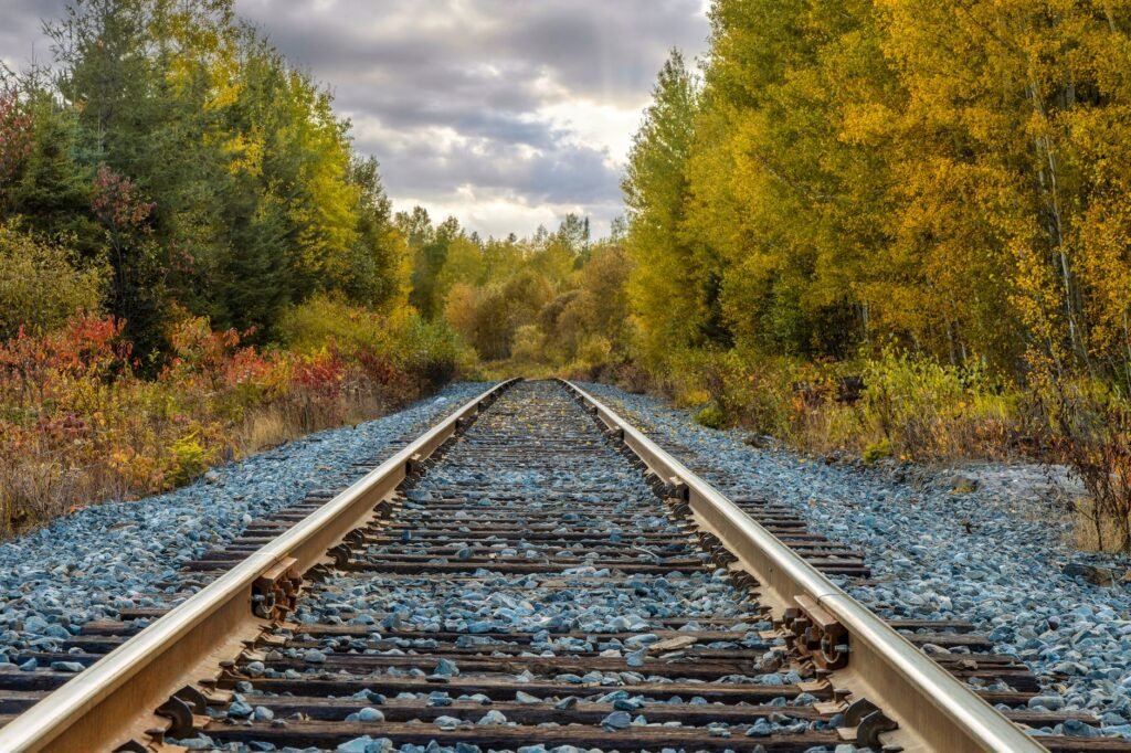 Explore the vibrant fall foliage along a serene railway track in Kirkland Lake, capturing the essence of autumn.