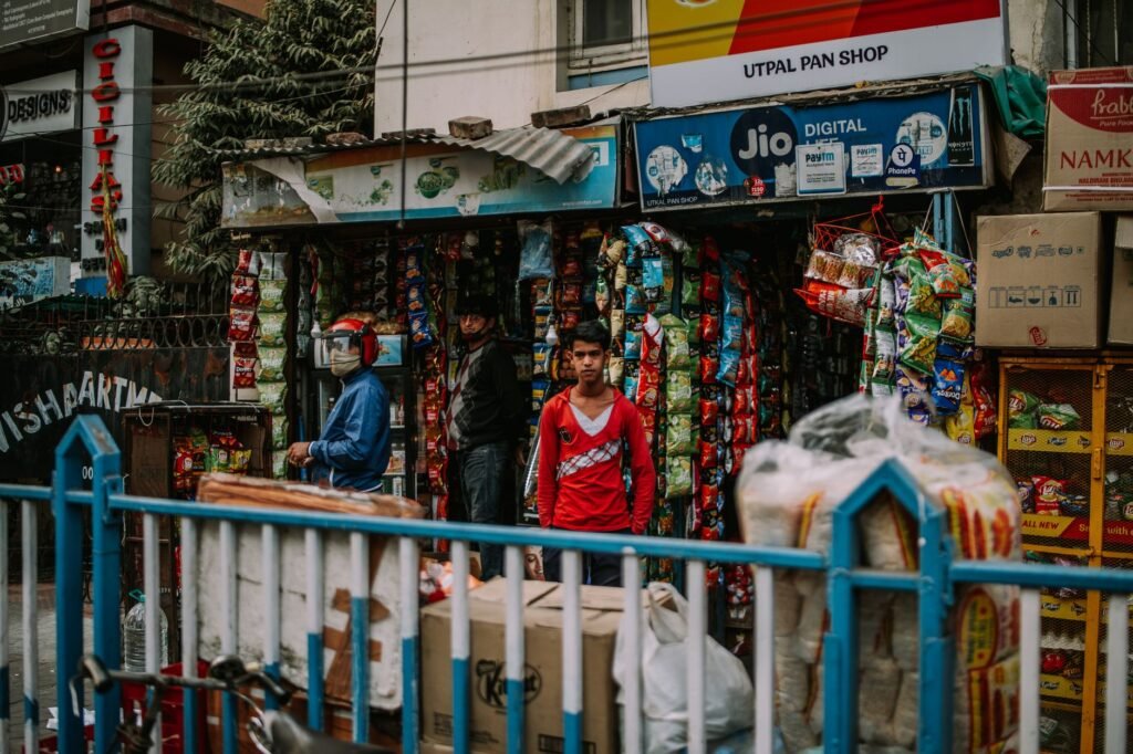 Street view of a small Indian shop bustling with vibrant colors and daily activities.