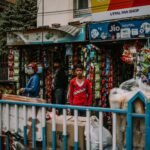 Street view of a small Indian shop bustling with vibrant colors and daily activities.