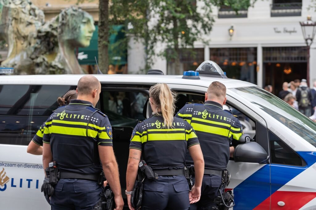 Police officers in uniform inspecting a vehicle on a busy city street, ensuring public safety.