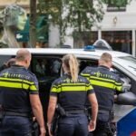 Police officers in uniform inspecting a vehicle on a busy city street, ensuring public safety.