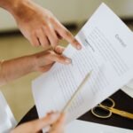 Close-up of two people discussing a business contract at a desk in an office setting.