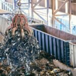An industrial claw crane lifts metal scrap in a recycling facility, showcasing efficient waste management.