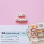 Top view of tax form, euro banknotes, and 'Pay Taxes' letter blocks on pink background.
