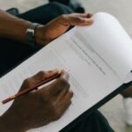 Close-up of a person writing on a psychological assessment form with a pencil.