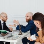 A lawyer mediates an emotional settlement discussion with a distressed couple in a legal office.