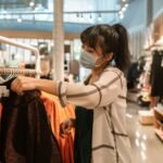 Woman wearing a face mask shopping for clothes in a department store.