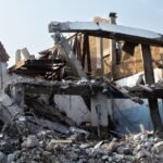 A partially demolished building showcasing exposed beams and rubble at an urban site.