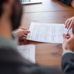 Close-up of business professionals reviewing documents at a meeting.