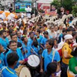 Vibrant parade in Kolkata with crowds, balloons, and cultural festivities.