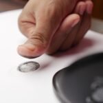 Detailed shot of a thumb creating a fingerprint on white paper, ideal for security themes.