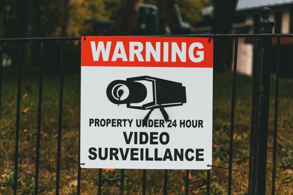 Video surveillance warning sign on metal fence outdoors.