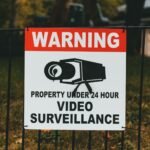 Video surveillance warning sign on metal fence outdoors.