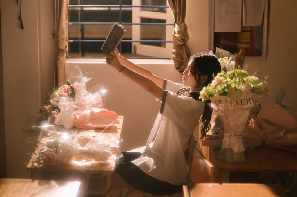 Young woman in Lạng Sơn, Việt Nam, enjoys a book amidst flowers in a sunlit room.