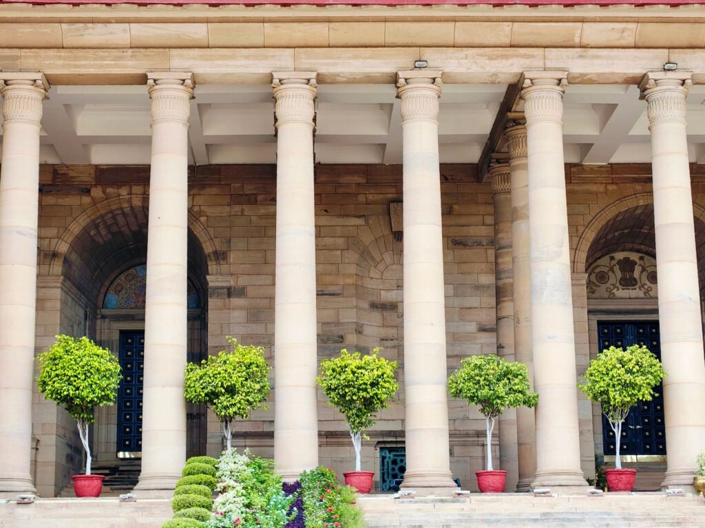Classical stone columns with potted greenery in Delhi, India, showcasing traditional architecture.