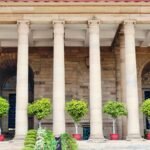 Classical stone columns with potted greenery in Delhi, India, showcasing traditional architecture.