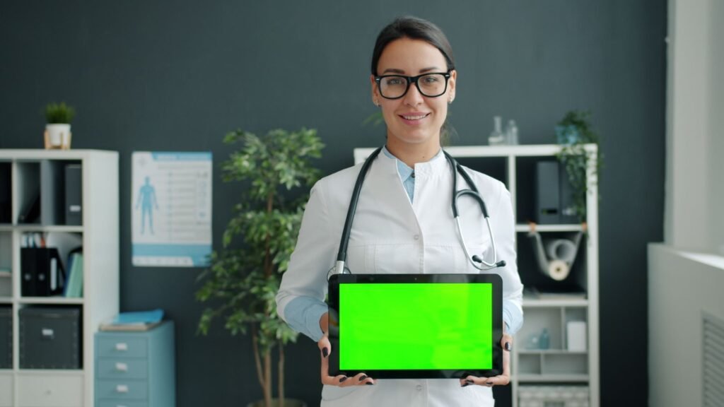 Female doctor smiling and holding a tablet with green screen in a modern office.