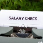Close-up of a vintage typewriter typing 'Salary Check' on paper, symbolizing payroll and finance.