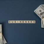 Top view of dollar bills and 'businesses' letter tiles symbolizing financial success.