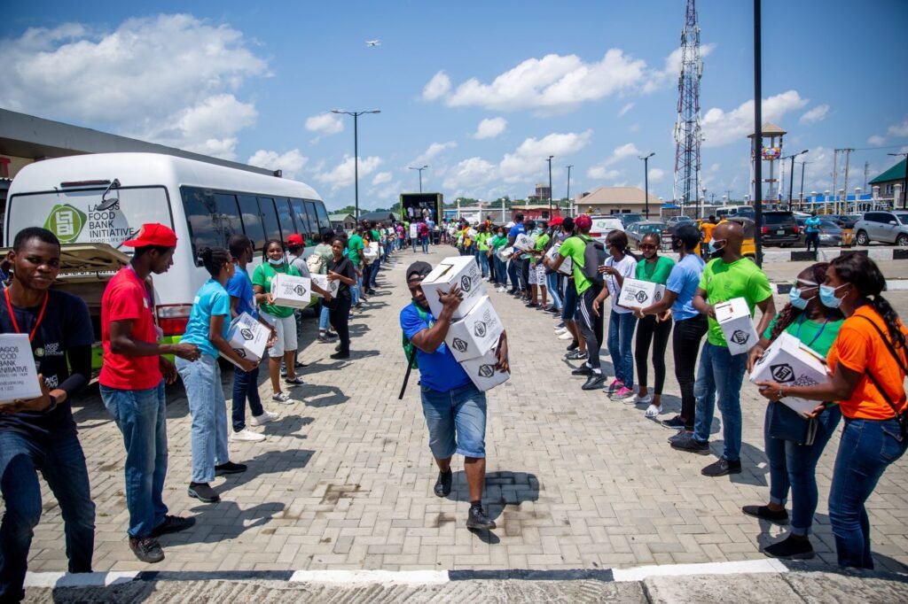 Volunteers in bright shirts organize and distribute donation boxes through a human chain outdoors.