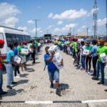 Volunteers in bright shirts organize and distribute donation boxes through a human chain outdoors.