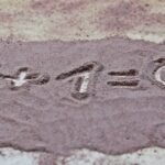 A heart symbol and math equation drawn in sand, symbolizing love.