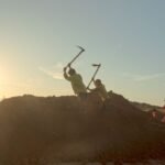 Silhouetted workers laboring at sundown in a rural Indian field, capturing daily life and environment.
