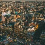 A vibrant aerial cityscape of Delhi, showcasing the bustling streets and diverse architecture under warm daylight.