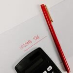 Close-up of a calculator and red pen on paper labeled 'Income Tax', representing financial planning.