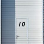 Sleek white metal wall with a numbered door, showcasing minimalistic design and industrial style.