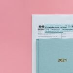 U.S. 1040 tax form with 2021 planner on a pastel pink background, symbolizing tax season.