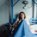 A young woman lying on a bunk bed with luggage in a cozy hostel room.