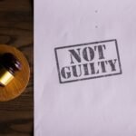 A courtroom document labeled 'Not Guilty' beside a gavel symbolizes justice.