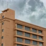 A modern building in Rajkot, Gujarat, India, under a dramatic cloudy sky.