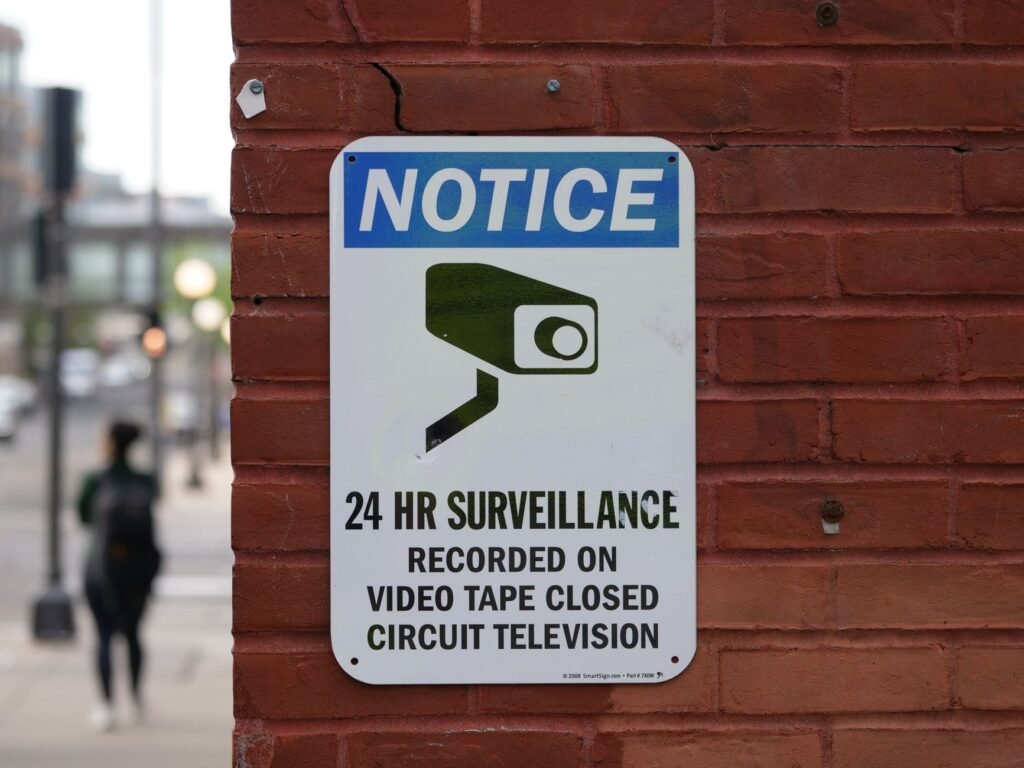 Close-up of a surveillance notice on a brick wall, urban setting.