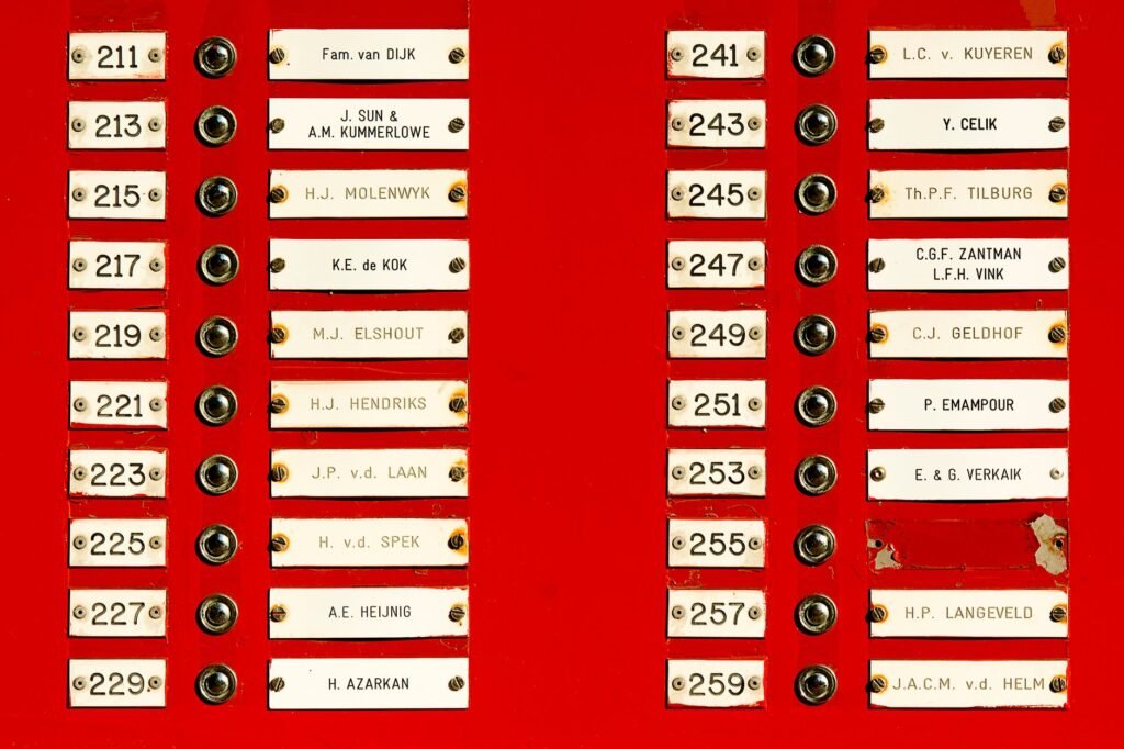 Close-up of a red doorbell panel with multiple nameplates and buttons in a building.