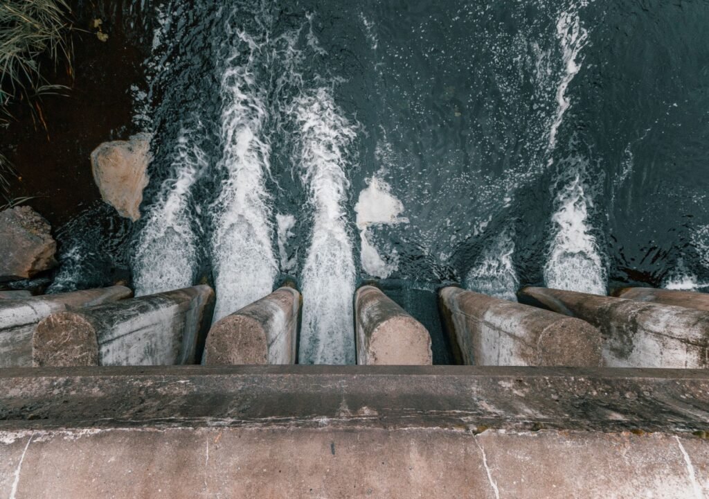Aerial view of cascading water over a concrete dam showcasing turbulent flow and water management.