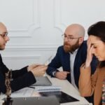 Lawyer discussing divorce settlement with distressed couple during tense meeting.