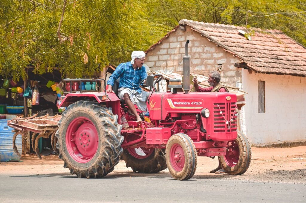 A farmer driving a red Mahindra tractor in Aranthangi, Tamil Nadu, India, showcasing rural life.