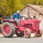 A farmer driving a red Mahindra tractor in Aranthangi, Tamil Nadu, India, showcasing rural life.