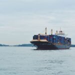 Large cargo ship transporting containers across a calm sea, symbolizing global logistics.