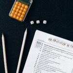 Flat lay of tax form, pencils, and calculator on black background, emphasizing tax deductions.