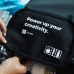 Hands holding a black bag with a creative slogan printed on it.