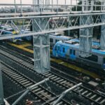 Aerial view of modern railways and blue train in urban setting, showcasing transportation infrastructure.