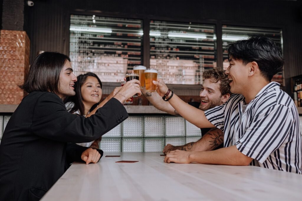 A diverse group of friends toasting with beers at a cozy bar, enjoying shared moments.