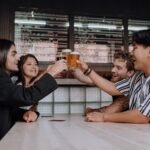 A diverse group of friends toasting with beers at a cozy bar, enjoying shared moments.